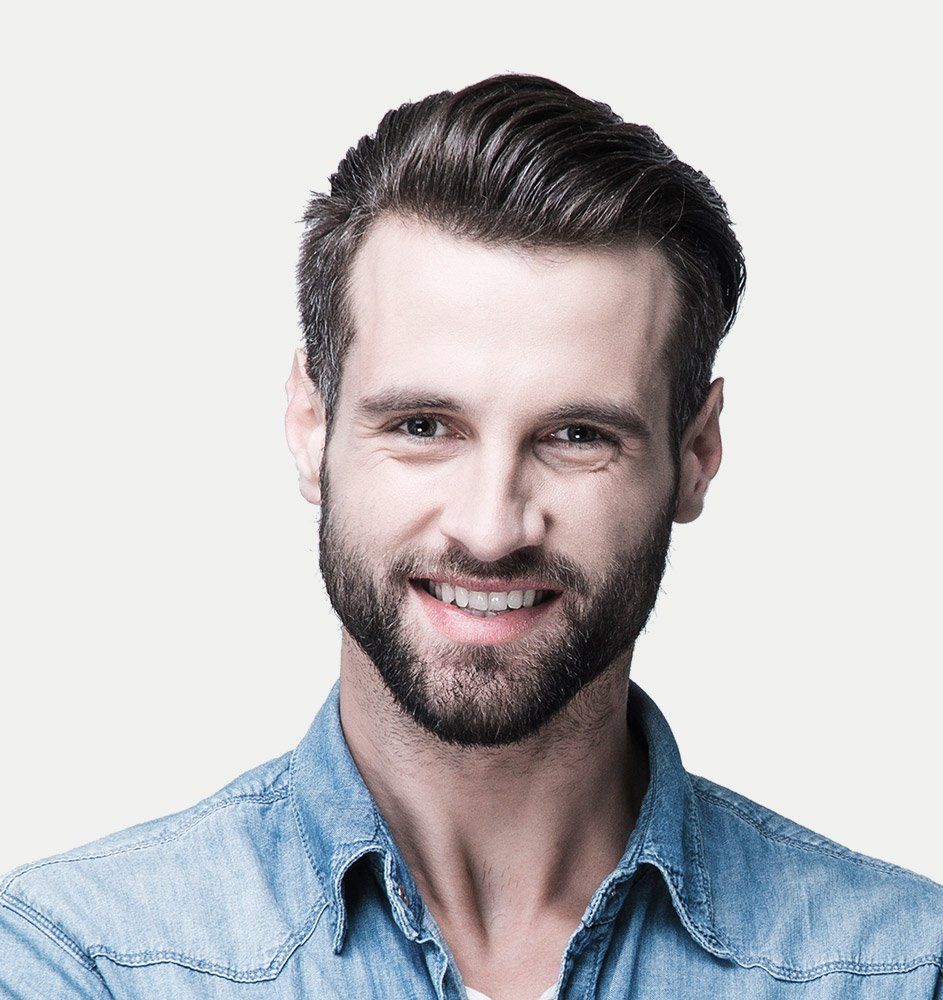 Man with a beard and dark hair, wearing a denim shirt, smiling at the camera.
